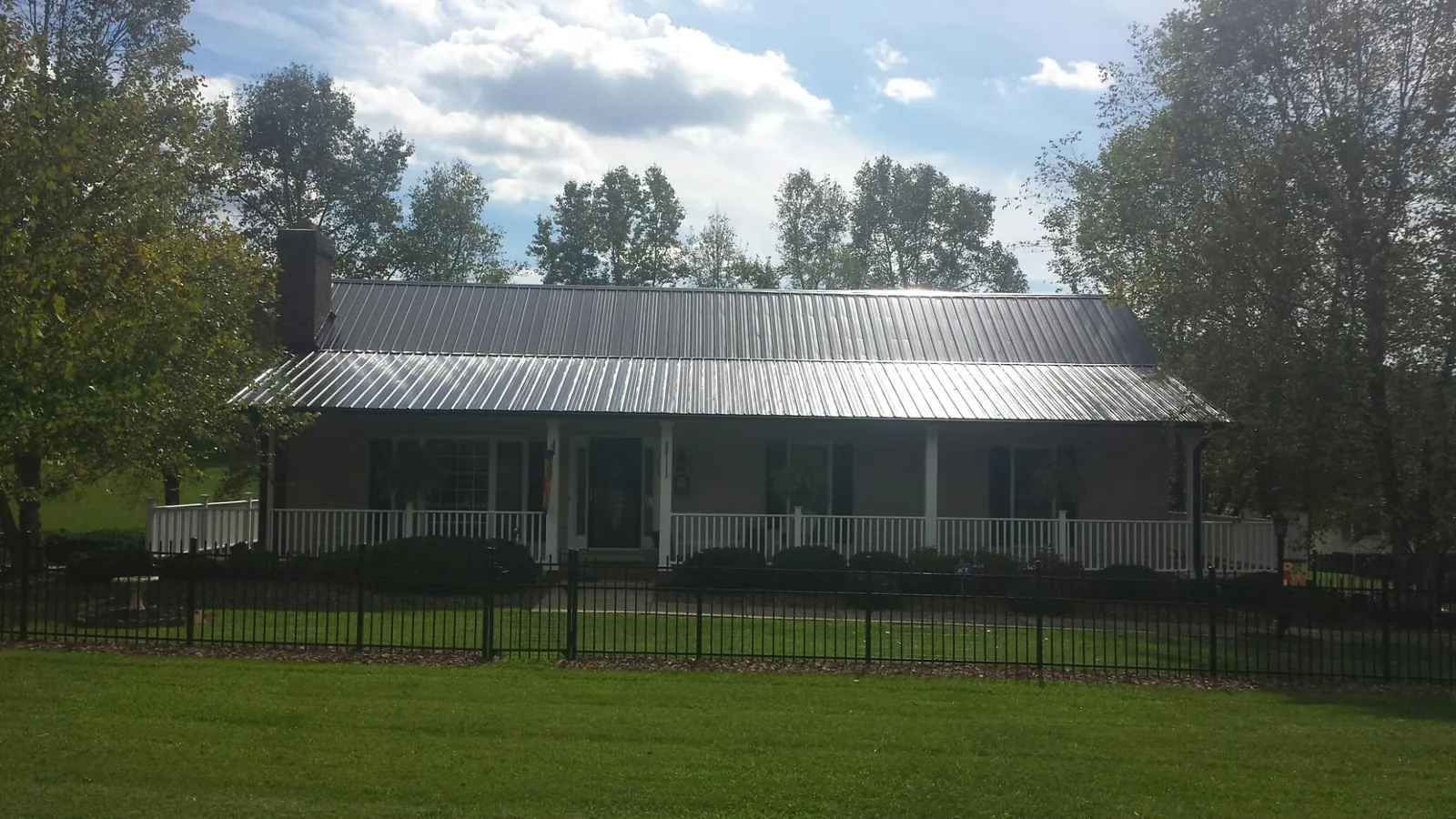 Gray metal roof on a brick ranch with a full width front porch — Gutter Guard Installation work by our crew in Walton