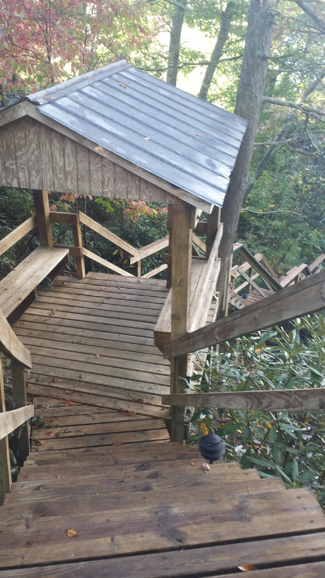 Metal roofed shelter over wooden steps on a wooded walkway — Skylight Repair & Installation work by our crew in Walton